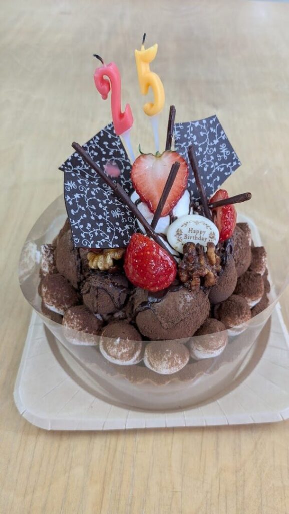 2と5の形をしたロウソクがさしてあるチョコレートケーキ